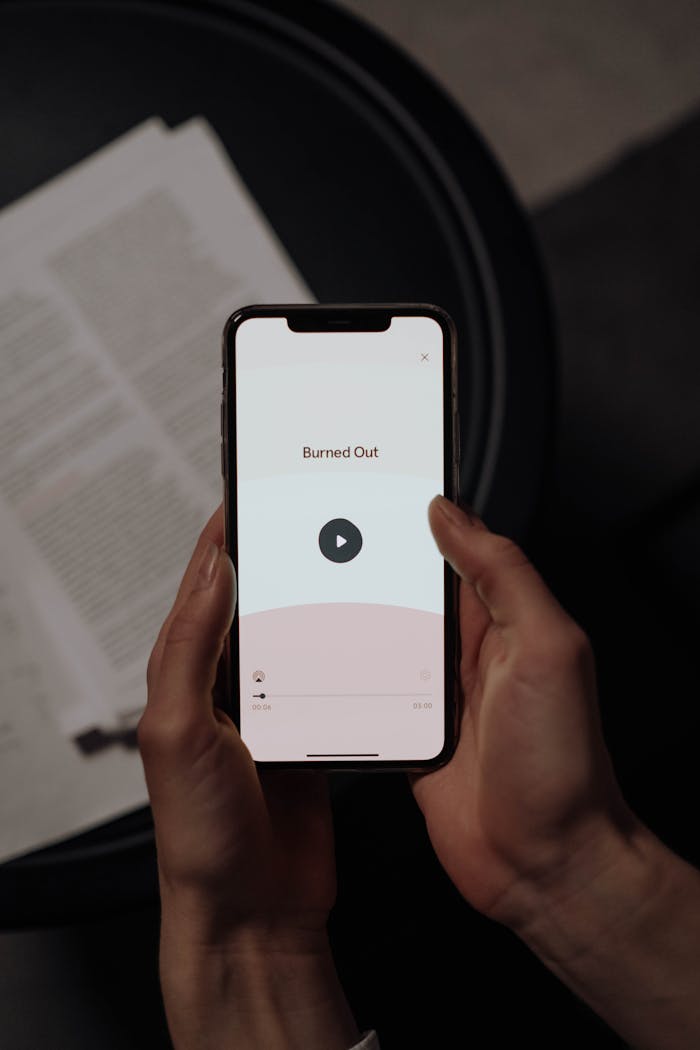 A close-up of hands holding a smartphone displaying a burnout application with a play button.